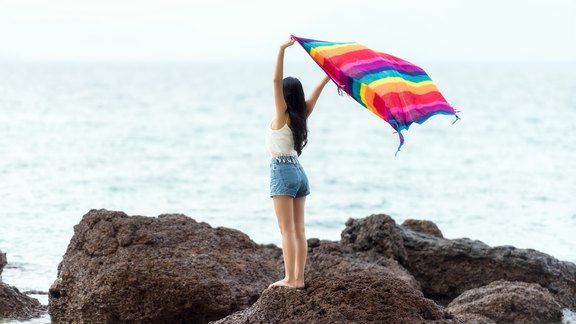 Junge Frau am Meer mit buntem Schal im Wind - Foto: SasinTipchau/pixabay